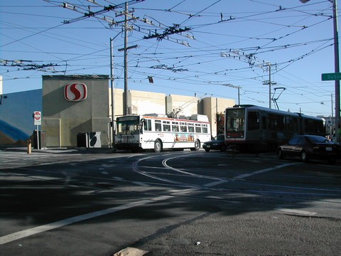 Here are the other two transit lines at this location.  The J-Church Light Rail Vehicle has just come out of the tunnel and made a left.  The 22-Fillmore trolleycoach is about to cross Duboce and the very complex special work here.  The nearest pair of overhead wires are the southbound 22's.  Notice the breakers connected by heavy cables above...there is no power for the buses for the length of the space between the breakers.  There are level parts going to the right, and it is uphill going to the left...and the car between the LRV and the bus will attempt to cut the bus off as the lanes merge as you cross the intersection.  Luckily the new buses have batteries.